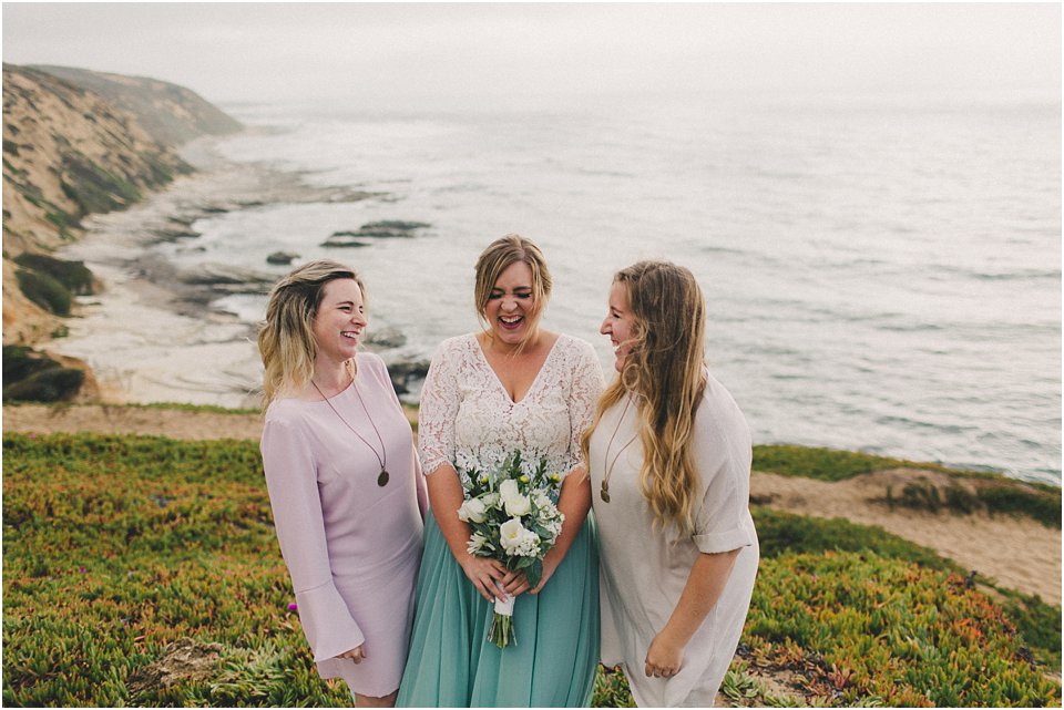 bride holds bouquet and laughs with a sister on each side