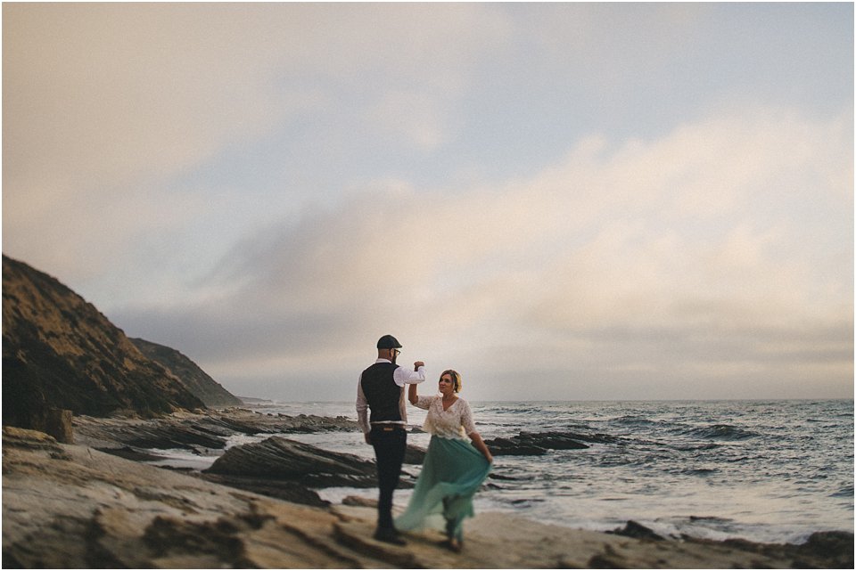 bride and groom dance on a rock overlooking the ocean after they eloped